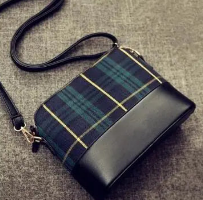 a black and blue plaid purse sitting on top of a floor