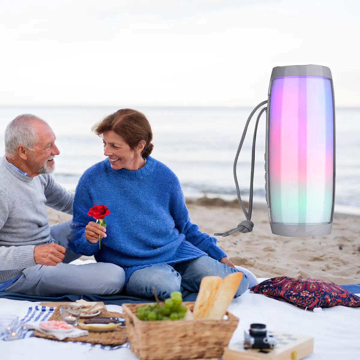 a man and woman sitting on a blanket on the beach