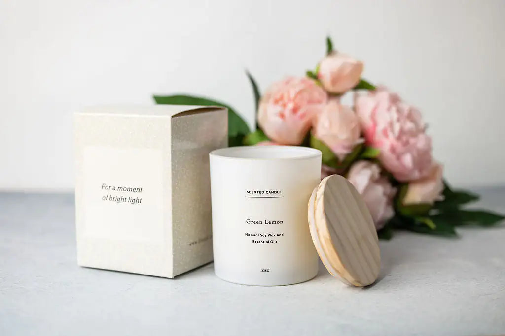 a white candle next to a box and flowers