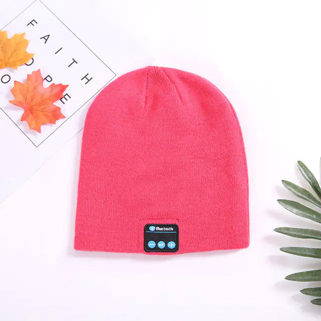 a pink beanie hat with a blue button on it