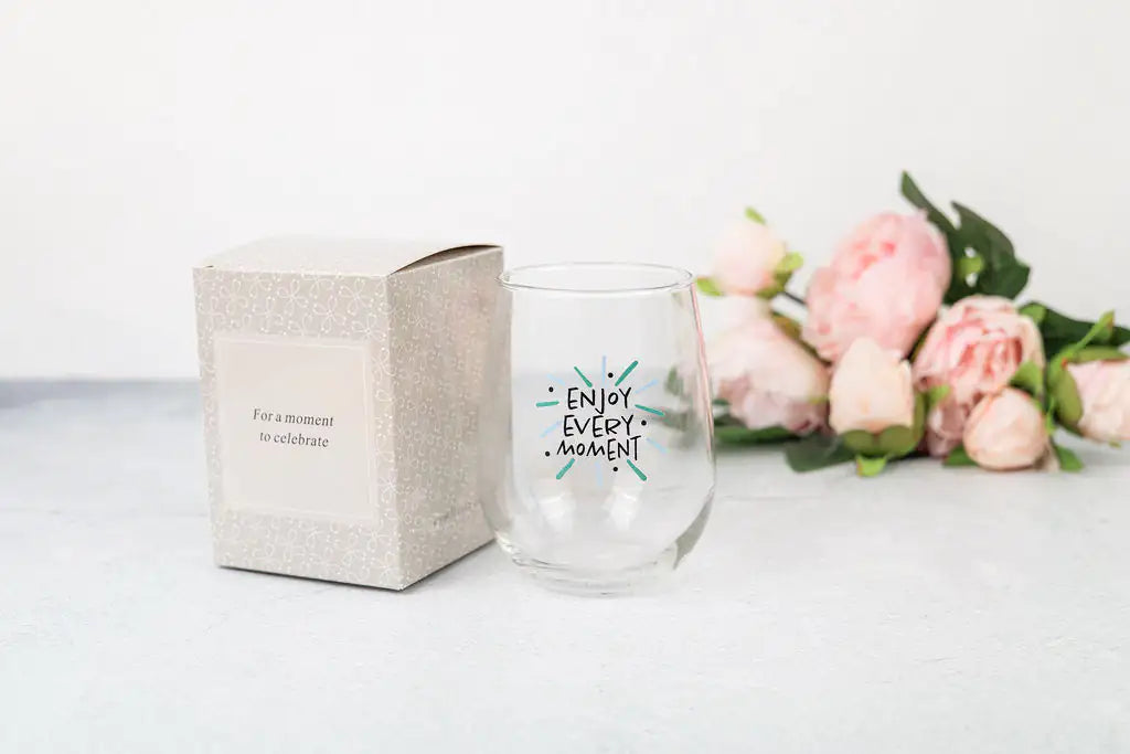 a wine glass sitting next to a box of flowers