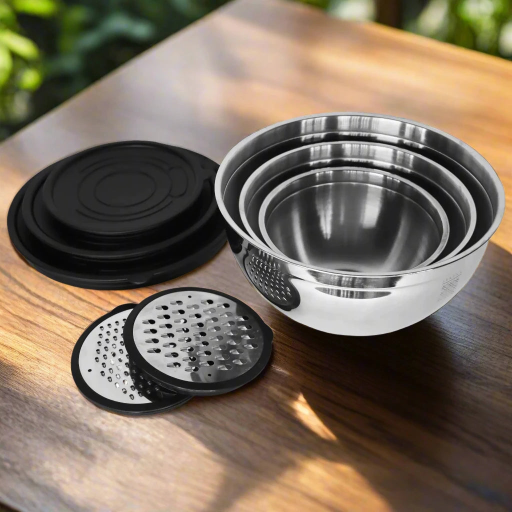 a set of four stainless steel mixing bowls on a wooden table