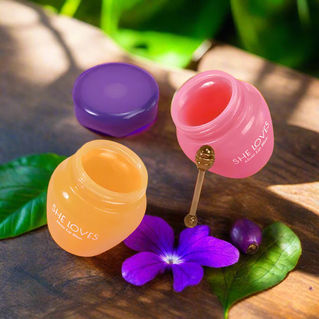 a bottle of lip glosses next to a purple flower