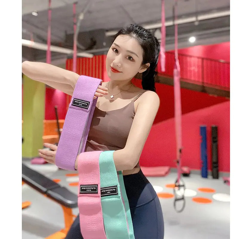 a woman holding a pink and blue belt in a gym