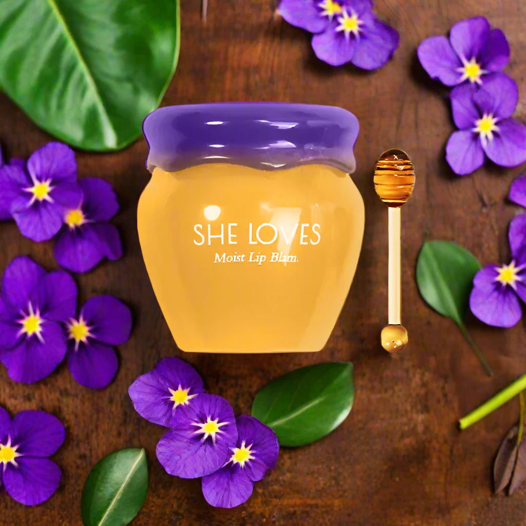 a jar of honey with purple flowers around it