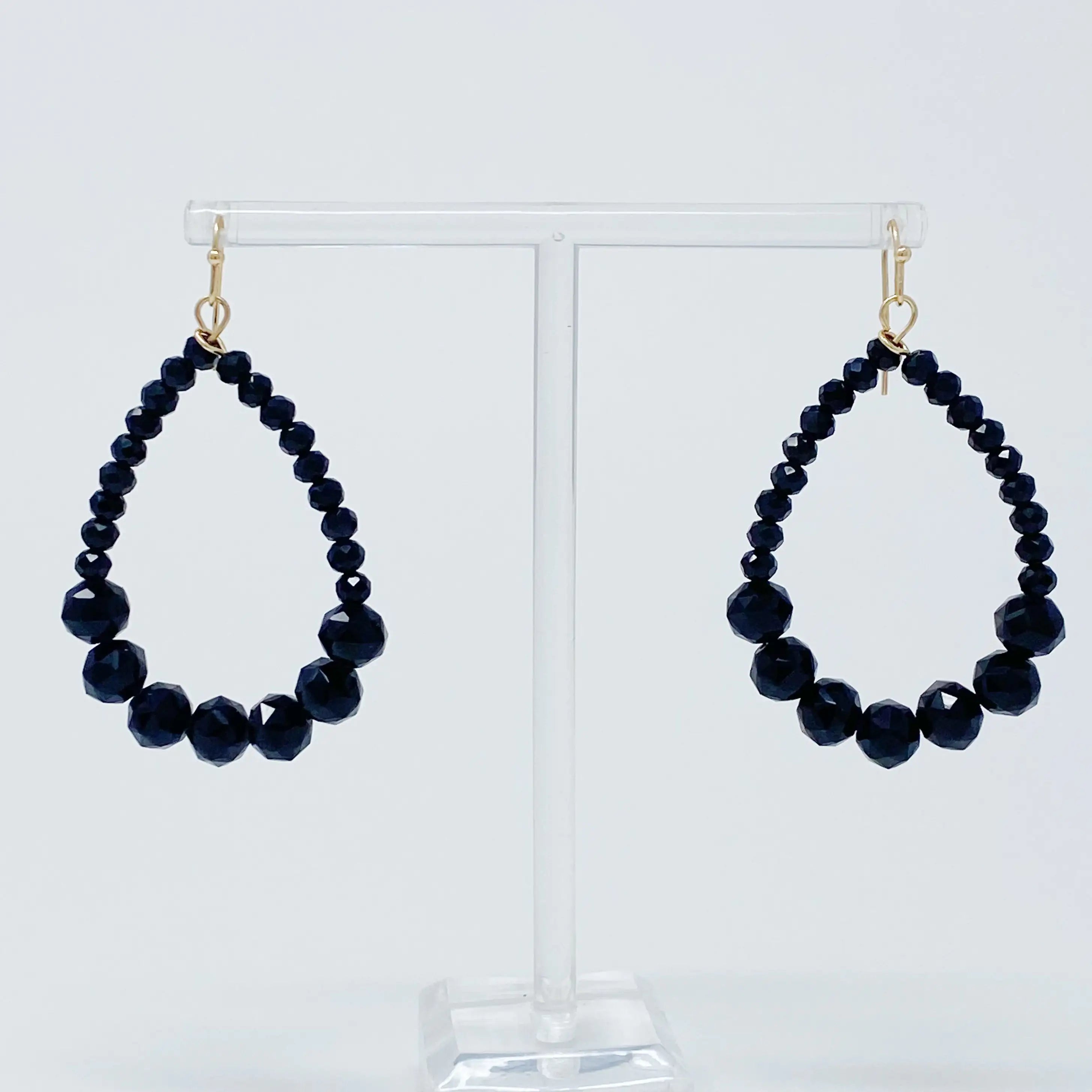 a pair of black beaded earrings on a stand