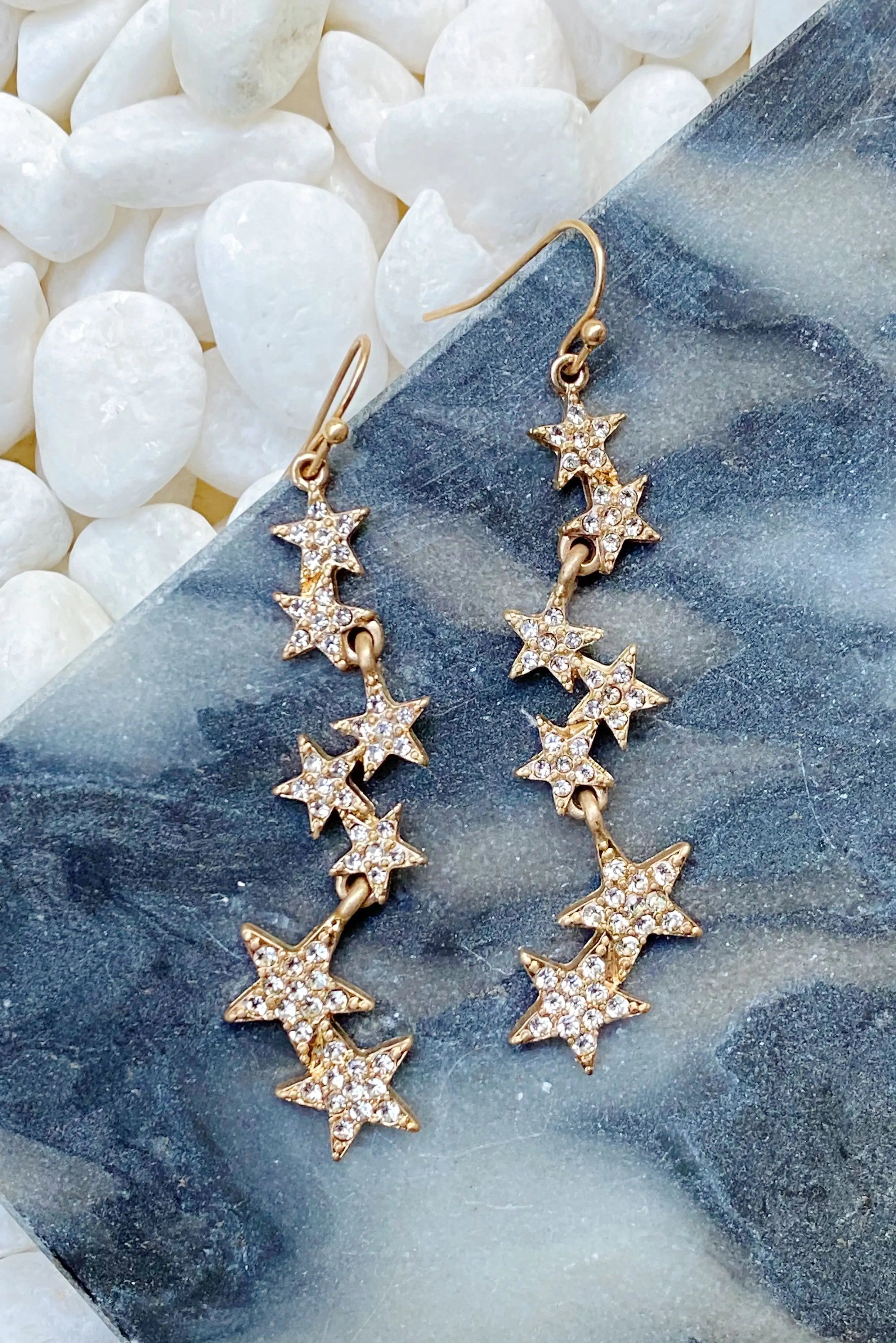 a pair of gold stars dangling from a pair of earrings