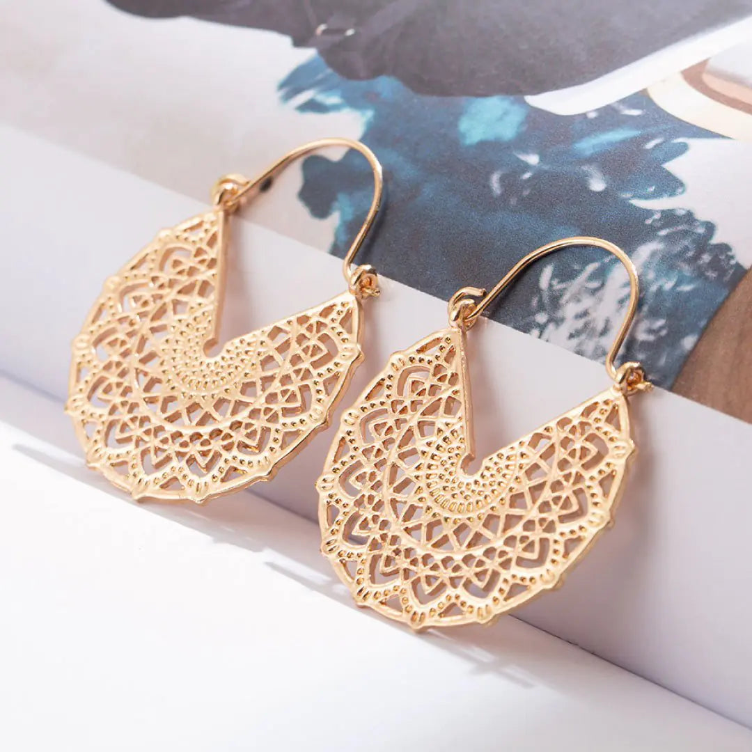 a pair of gold earrings sitting on top of a book