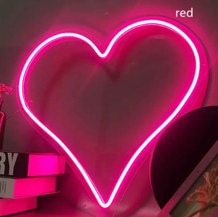 a heart shaped neon sign sitting on top of a shelf