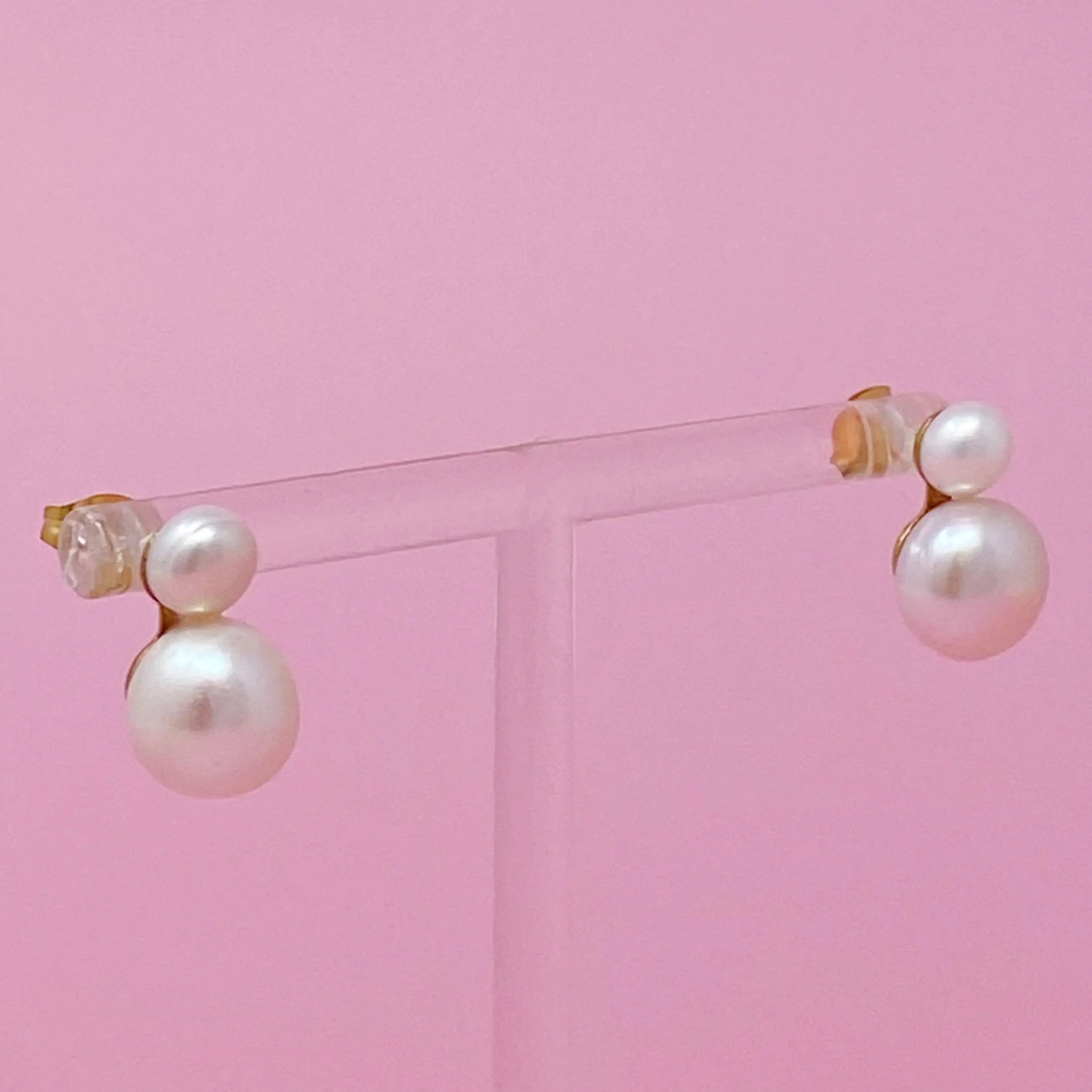 a pair of pearl earrings on a pink background