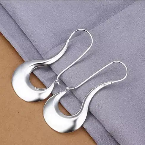 a pair of silver earrings sitting on top of a table